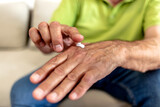 Cropped shot of an unrecognizable mature man applying moisturizer on hands. Elderly man with very dry skin applying moisturizing lotion on his hands. Grooming, body care and people concept.