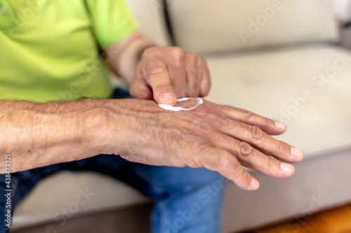 An older man using hand cream against varicose veins. Men s hand using moisturizing cream  skin and hand care. Close up view of mature male hands moisturizing his hands with cream. Copy space.