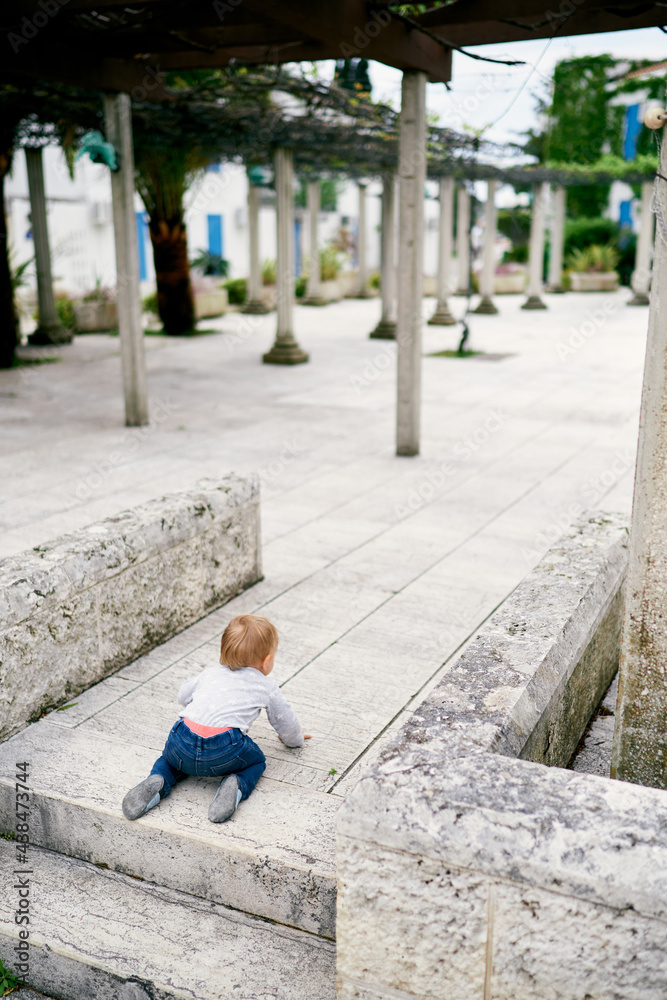 Kid crawls on the paving slabs in the courtyard of the house