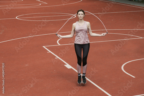 Young woman skipping jump rope on a sport field  © triocean
