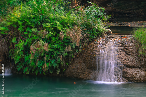 Fototapeta Naklejka Na Ścianę i Meble -  A corner of the waterfall flowing through the rocks and trees.