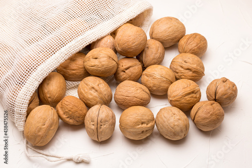 Walnuts in a pouch, part rolled out on a white background. Inshell walnuts. Healthly food. photo