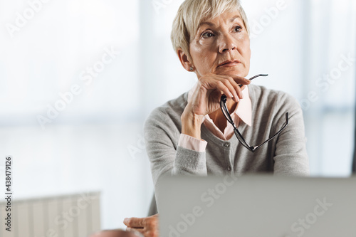 Thoughtful businesswoman working on laptop in the office photo