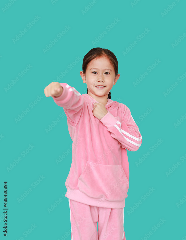Funny little Asian child girl in pink tracksuit or sport cloth with fight expression isolated on green background. Portrait half-length of kid. Confident concept. Funny little Asian child girl in pink tracksuit or sport cloth with fight expression isolated on green background. Portrait half-length of kid. Confident concept.