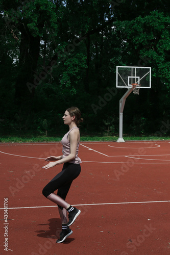 Fit young woman doing a dynamic exercise on a sport field. Cardio training outdoors. 