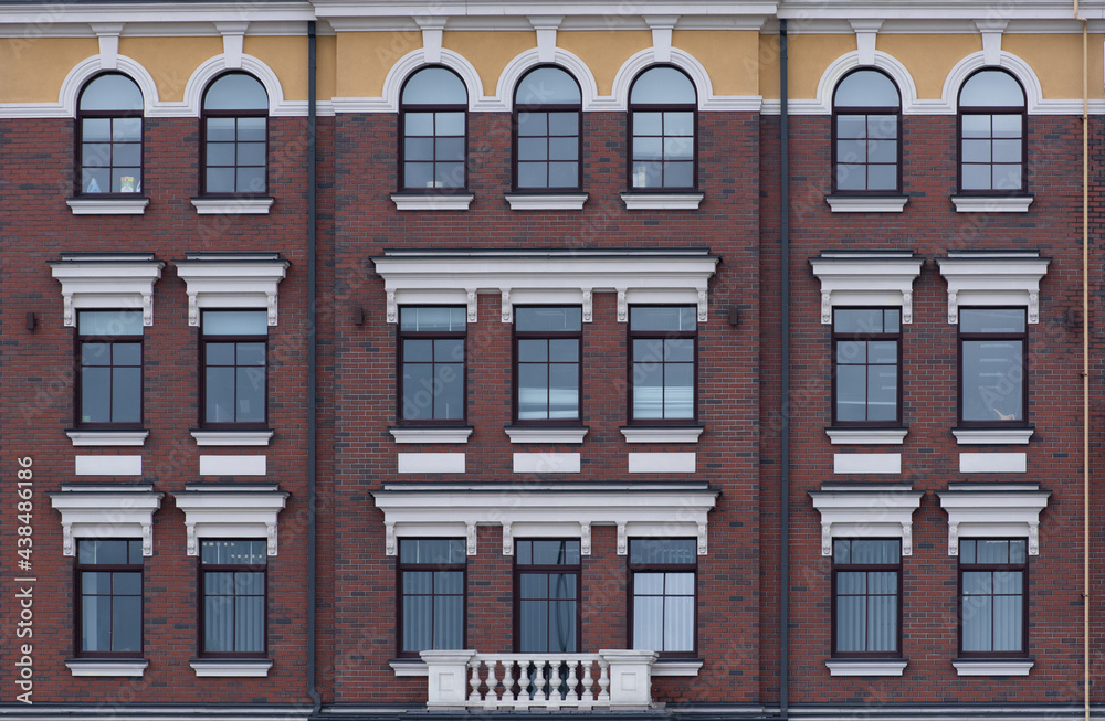 Texture of the building with red brick and white decor on the windows.