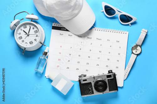 Calendar, alarm clock and female accessories on color background