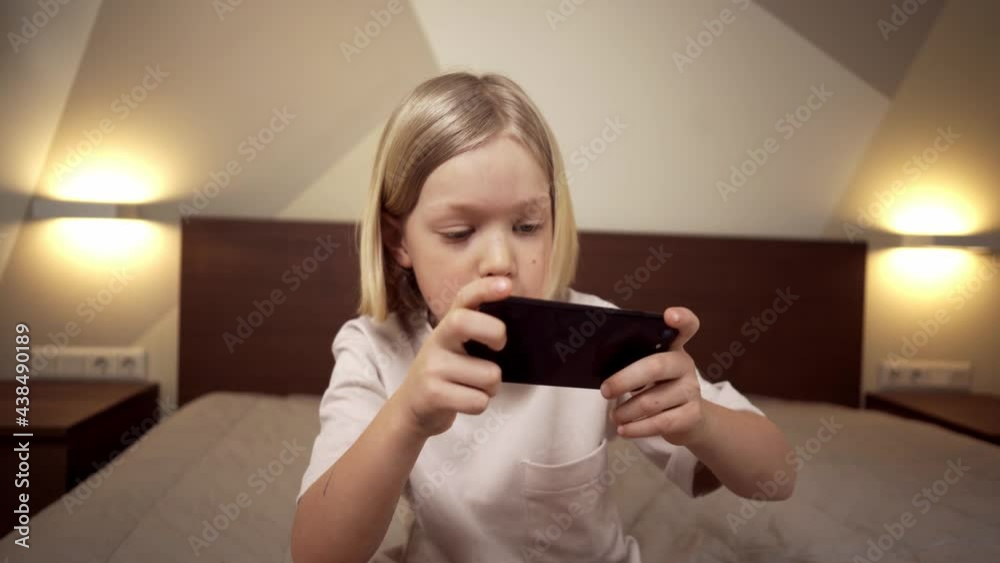 Blonde boy playing games on the phone. Blonde boy playing games on the phone.
