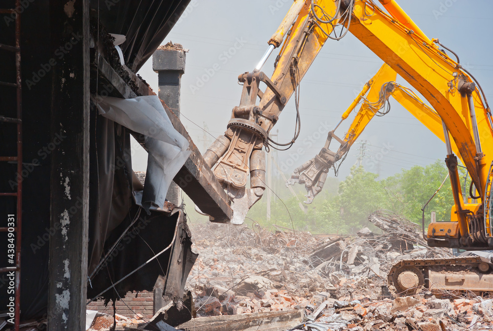 Fototapeta premium Two demolators destroy the building and remove the debris.