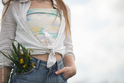 spring in your pocket. A bouquet of wildflowers sticking out of the jeans pocket of a teenage girl