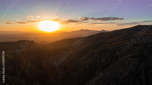 Aerial view of  mountains in Arizona during sunset with silhouettes in the distance and clouds. © Victoria