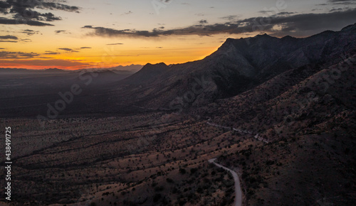 Sunset behind Arizona mountains with a road and several mountain peaks