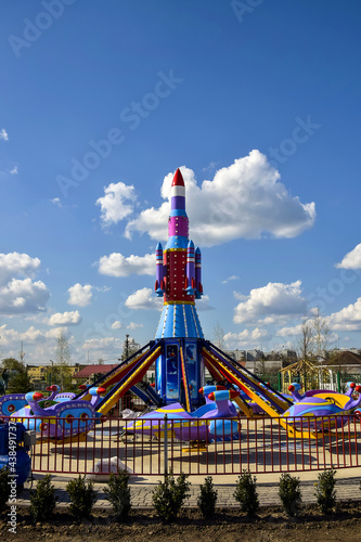 Children's attraction is quarantined due to Covid-19. Colorful carousel in form of rocket against blue sky with fluffy clouds. Close-up. Selective focus.