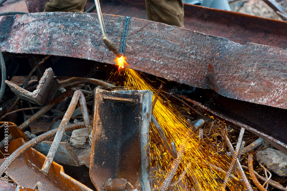 A worker cuts an iron beam with a gas cutter.