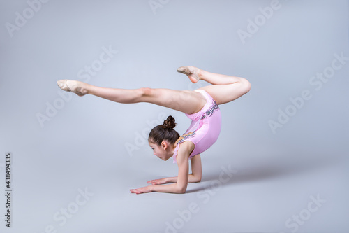 Gymnast in a pink suit isolated on a gray background