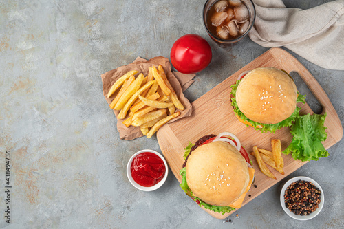 Hamburgers, French fries and cola on a gray background. Fast food.