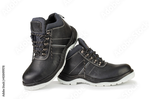 A pair of black leather work boots with thick gray soles on a white background. The shoes are new and clean. The laces are untied. The image is isolated. The boots are in the center and have a shadow.