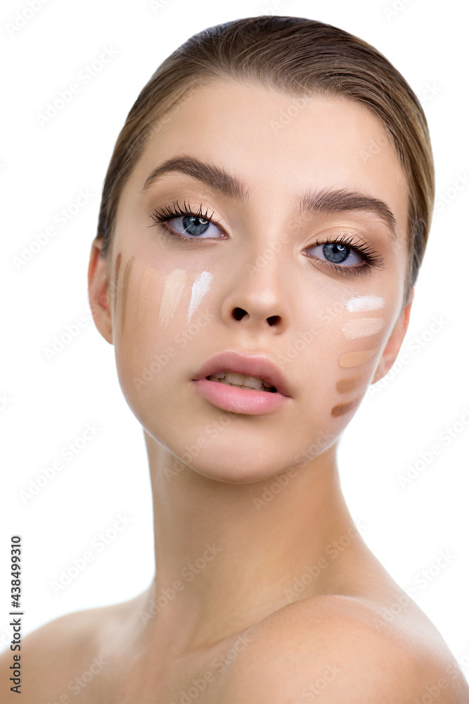 Young woman applying several color samples of facial foundation cream at her face. Young woman applying several color samples of facial foundation cream at her face.