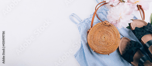 Women's fashion summer clothes. Stylish female straw hat, blue dress, rattan bag, peony. Banner