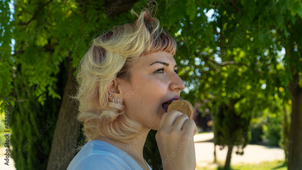 chica joven comiéndose un helado en el parque , chica de pelo corto y ojos claros con un helado en la mano chica joven comiéndose un helado en el parque , chica de pelo corto y ojos claros con un helado en la mano