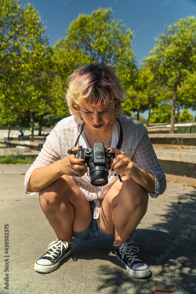 Chica joven con una cámara réflex en la mano, chica fotógrafa con blusa  blanca y pantalones