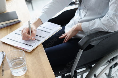 Disabled woman in wheelchair filling out application for employment closeup