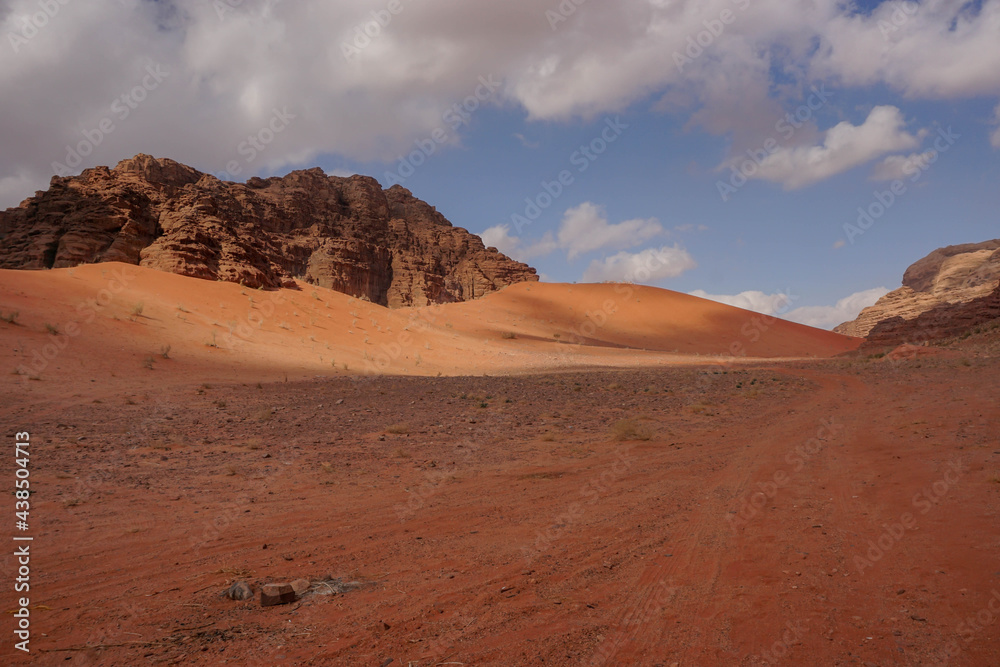 view of sand dunes and red relief mountains in the Wadi Rum desert, contrasting shadows are on the ground, nature of jordan