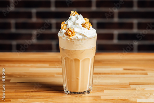 Photography Iced coffee cafe latte with cream and caramel popcorn on bright table, coffe shop