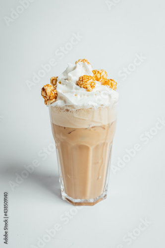 Iced coffee cafe latte with cream and caramel popcorn on bright table, coffe shop.