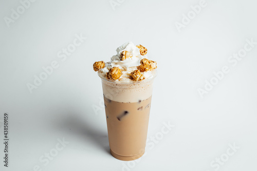 Iced coffee cafe latte with cream and caramel popcorn on bright table, coffe shop.