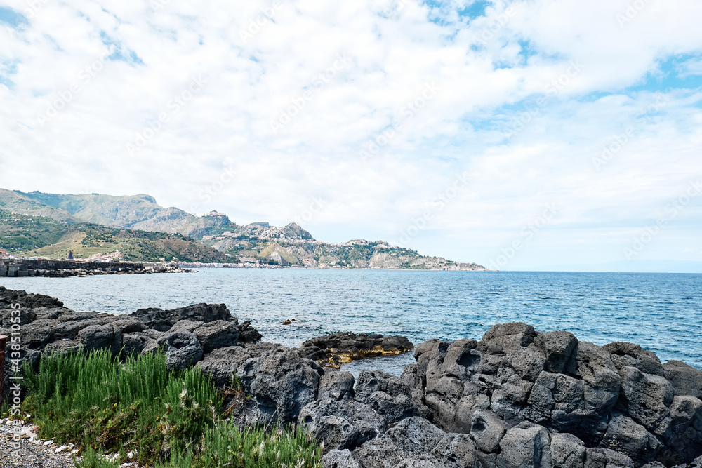 View of the gulf of Giardini Naxos with solidified volcanic lava. Beauty in Sicily as a tourist attraction. Season on mediterranean sea. Ionian sea.