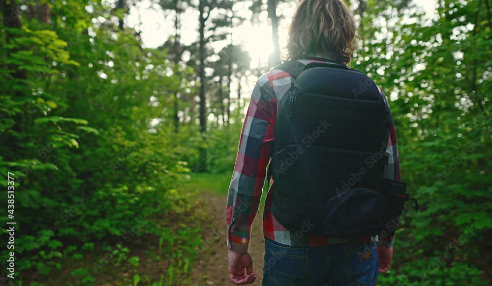 Man with backpack and sunglasses in the woods. Arc shoot.