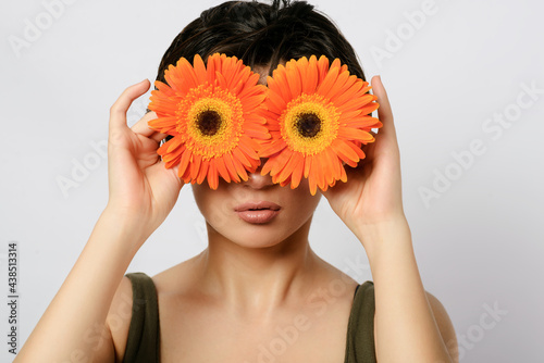 Woman smiling and holding flowers in front of her eyes.