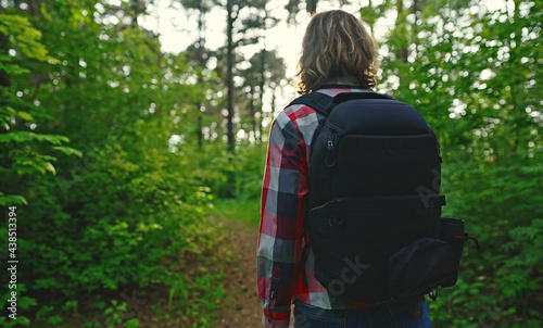 Man with backpack and sunglasses in the woods. Arc shoot.