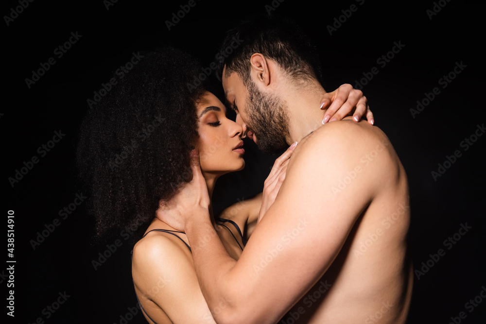 Side view of shirtless man kissing african american woman isolated on black Side view of shirtless man kissing african american woman isolated on black