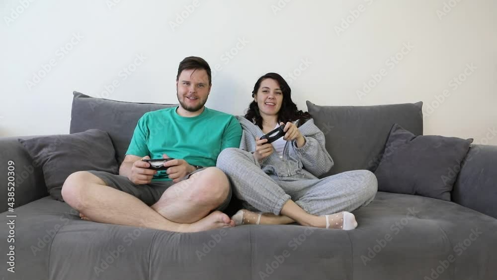 couple together playing video games sitting on couch couple together playing video games sitting on couch