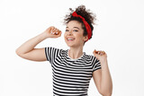 Carefree attractive woman in headband, dancing and having fun, smiling and laughing relaxed, resting at party, standing against white background