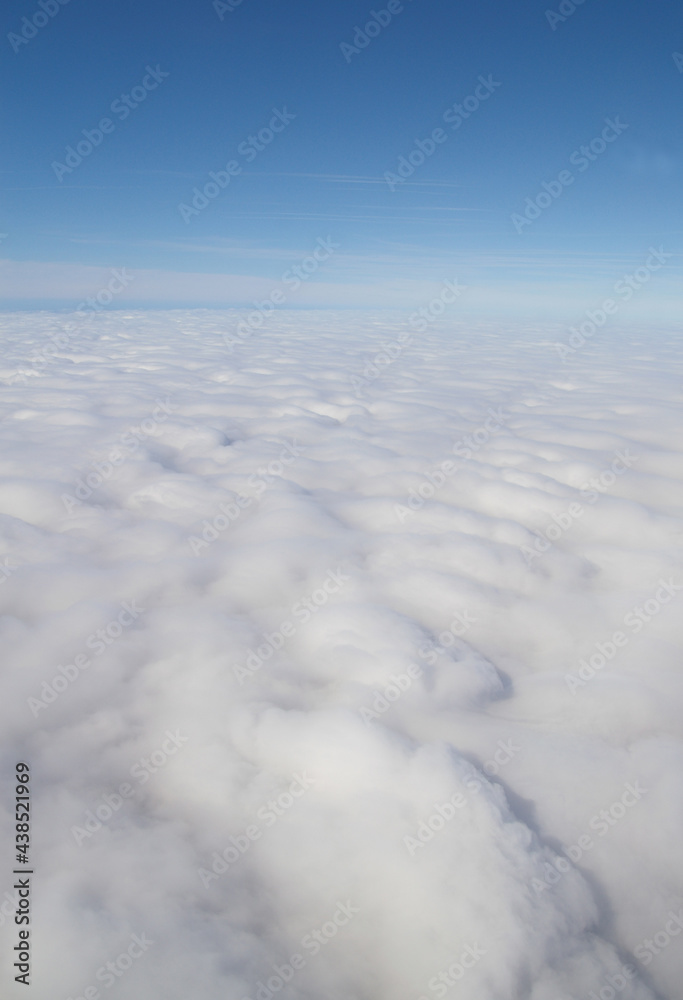 Aerial view of blue sky and horizon above fluffy white clouds