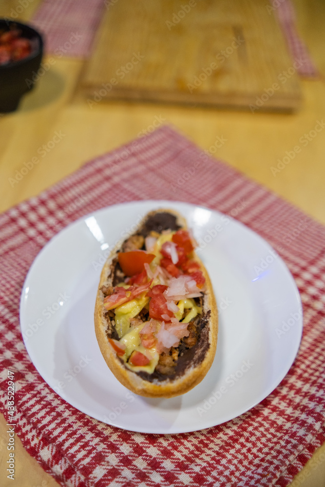 Traditional Mexican mollete on a plate above white and red checkered napkin