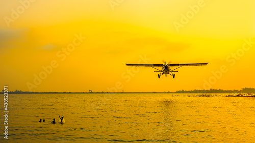 View of the lake with a low flying airplane and an unidentified people in the lake