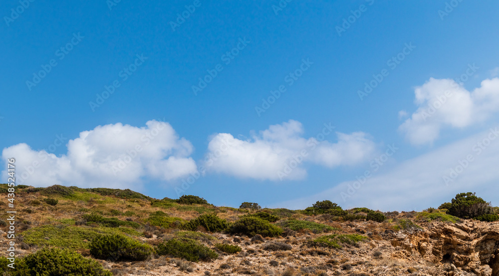 Steppe Greece terrain landscape with scenic cloudscape on blue vivid sky. Natural south Europe rocky bushy view