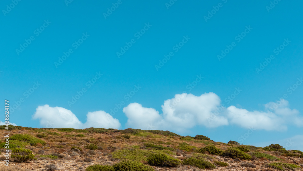 Steppe Greece terrain landscape with scenic cloudscape on blue bright vivid sky. Natural south Europe rocky bushy view