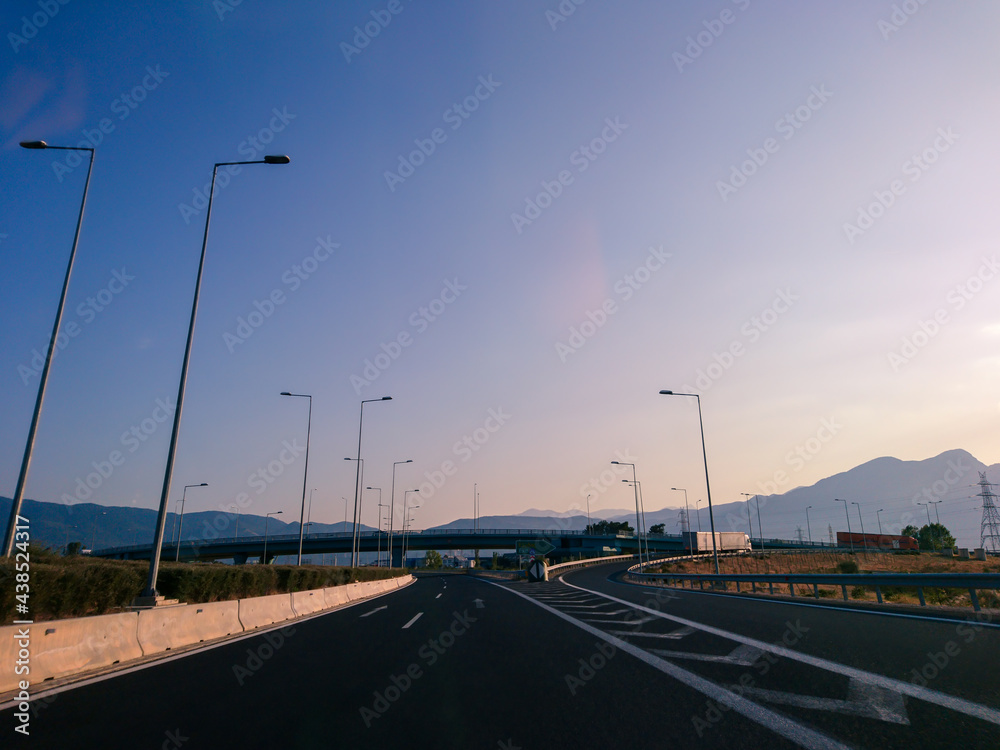 Driving autobahn asphalt road in Greece, Europe. Trip from Thessaloniki to Athens. Sunset sunny clear mountains silhouettes view in automobile journey