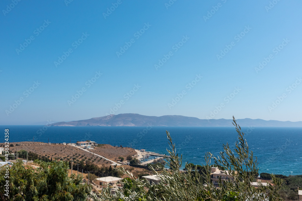 Sunny summer sea coast in greek village with green olive trees. Aegean sea shore in Greece, countryside near Athens