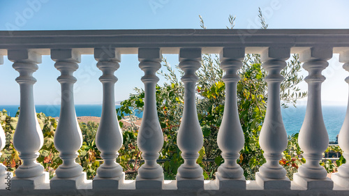 Traditional Greek architecture white balcony balusters. View on clear blue Aegean sea coast. Summer scenic view from country house terrace near Athens, Greece
