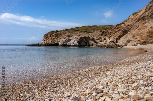 Fototapeta Naklejka Na Ścianę i Meble -  Wild mediterranean sea pebble beach close-up with rocky cliffs shore and blue clear water. Travel Greece near Athens. Summer nature scenic lagoon