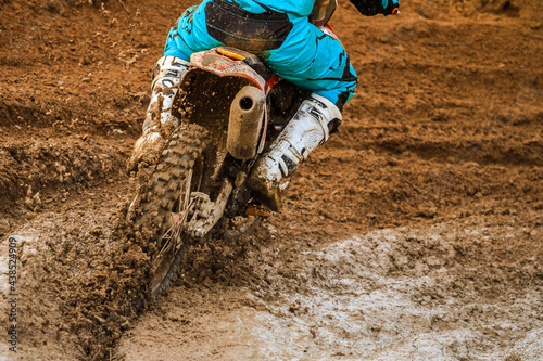 Close up of motocross racer accelerating in dirt track.