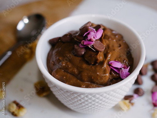 Chocolate mousse in a ceramic bowl with chocolate and pink garnish