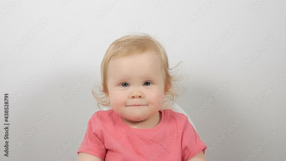 Smiling little baby wearing pink jumper sitting in feeding chair posing isolated on white background Smiling little baby wearing pink jumper sitting in feeding chair posing isolated on white background