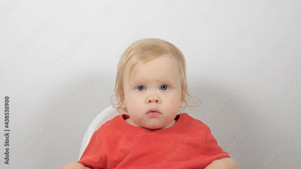 Medium closeup portrait of cute little kid wearing red domestic pajamas sitting in feeding chair Medium closeup portrait of cute little kid wearing red domestic pajamas sitting in feeding chair
